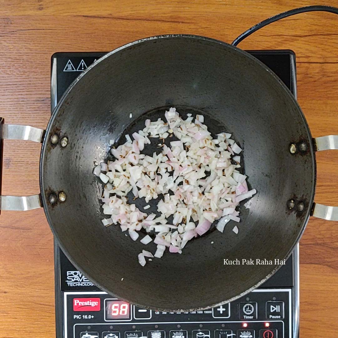 Sautéing jeera and onions in a pan.