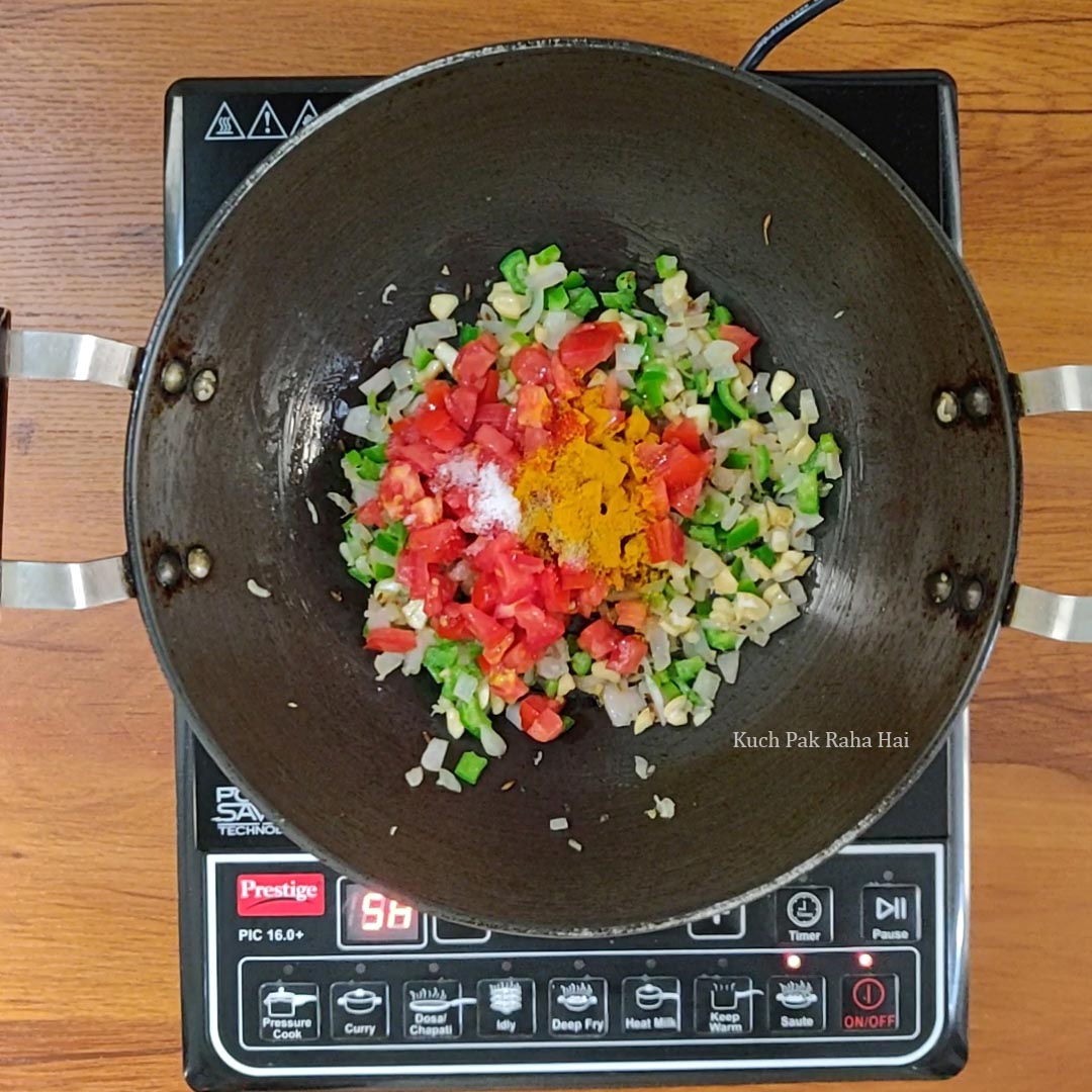 Adding tomatoes and spices to the pan.