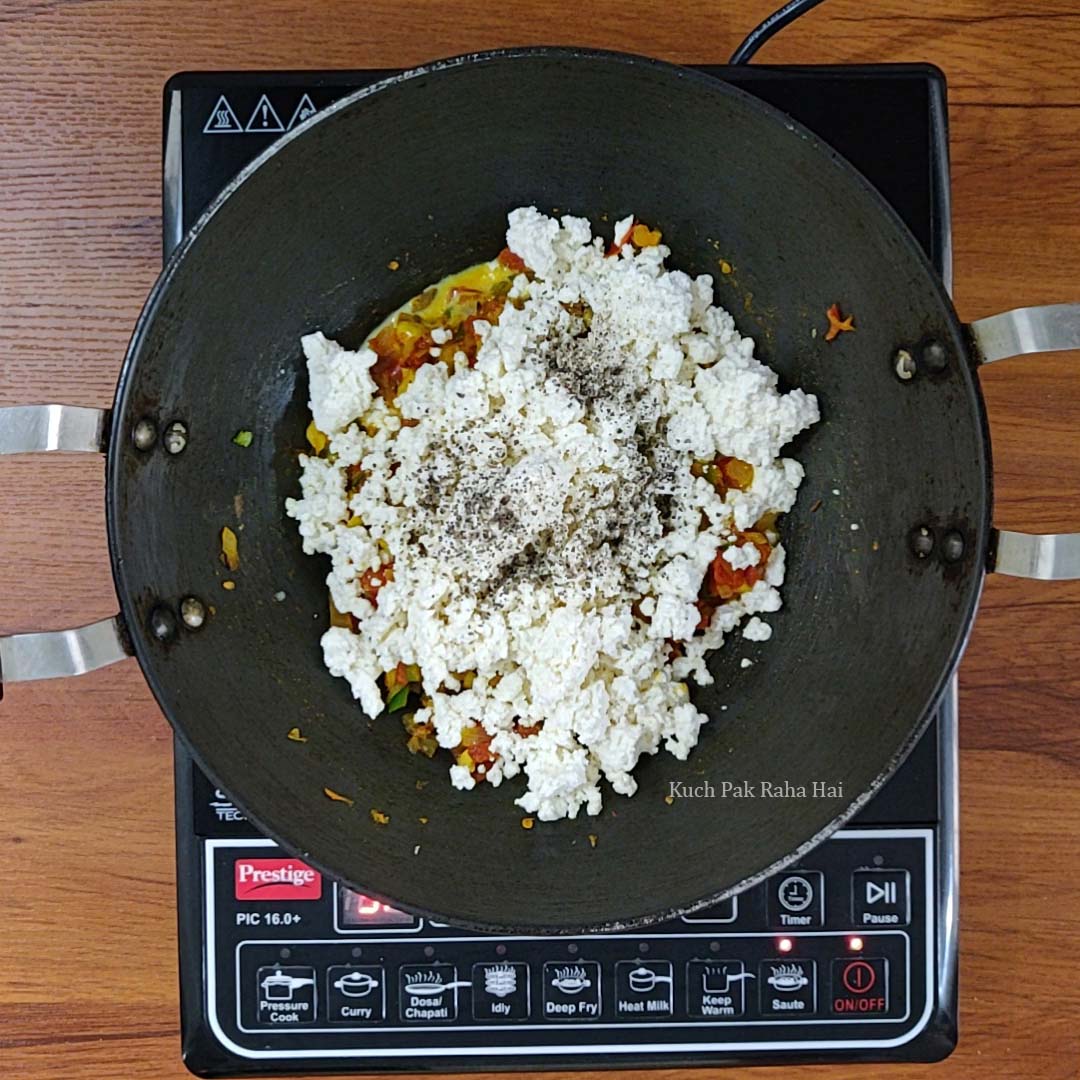 Adding crumbled paneer to cooked vegetables.