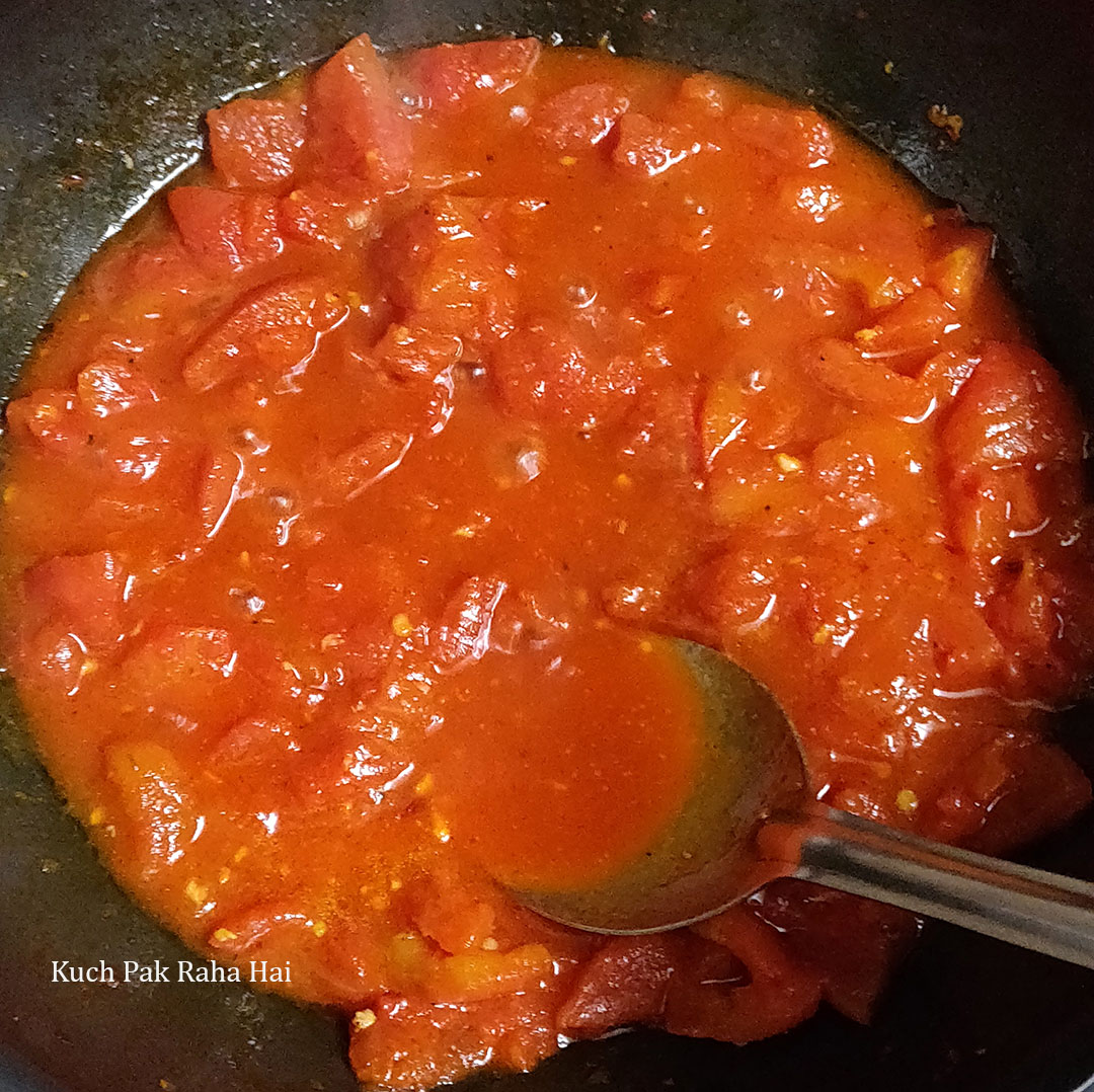 Mashing tomatoes with back of spoon.