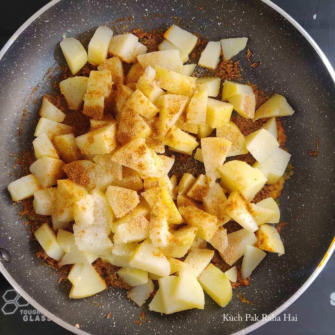Adding boiled chopped potatoes to spices.