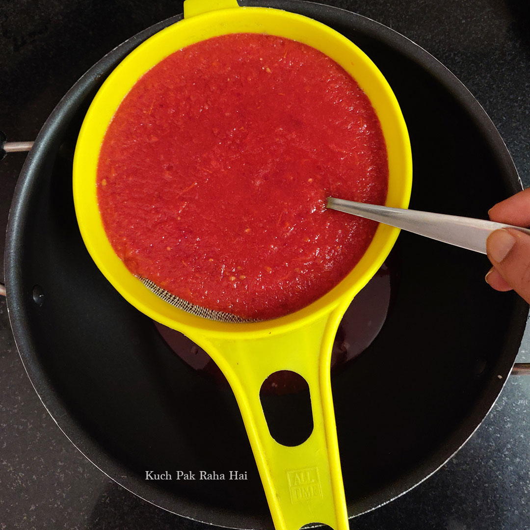 Passing the tomato soup through a sieve for removing seeds.