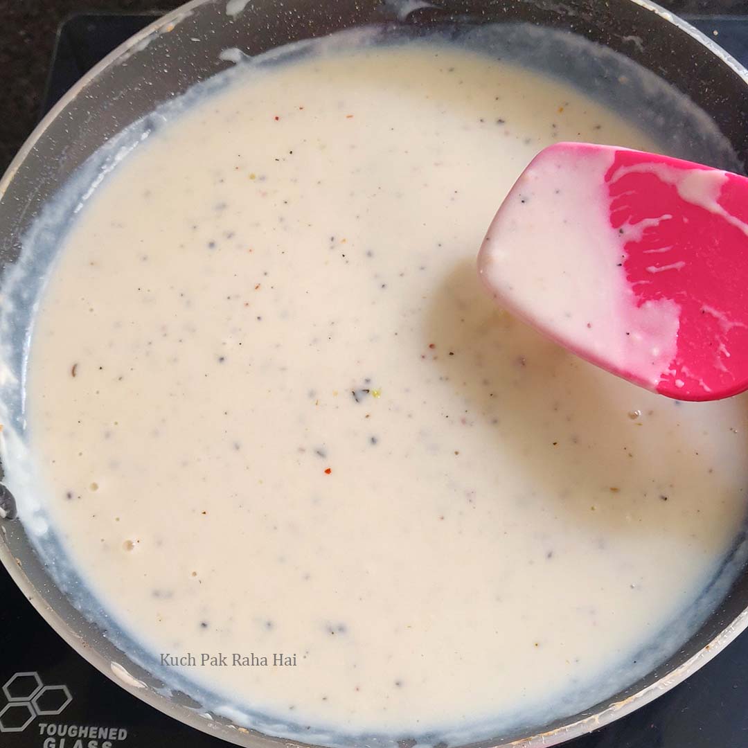 Adding seasoning to white sauce.