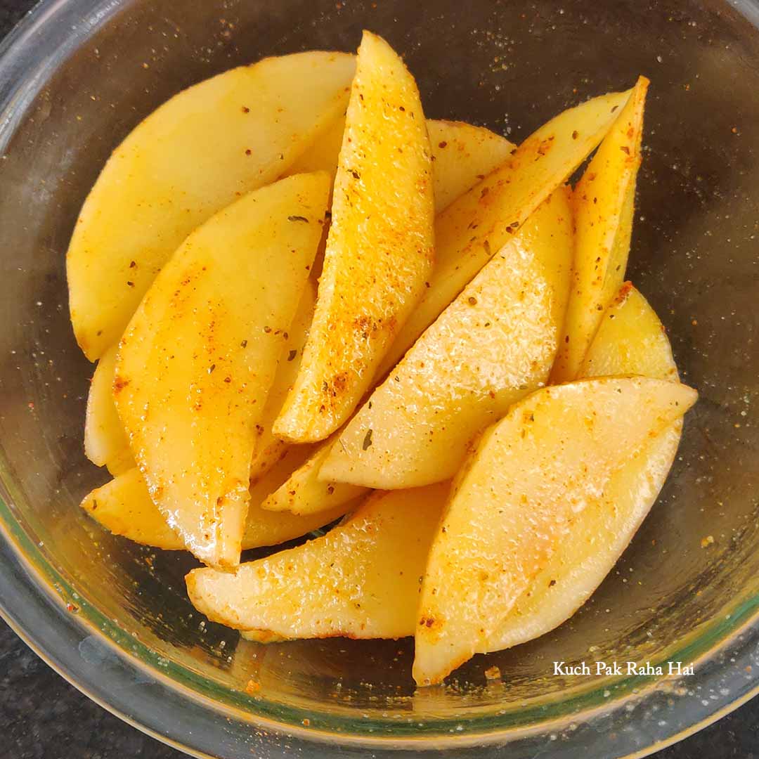 Rubbing oil & spices on potato wedges.