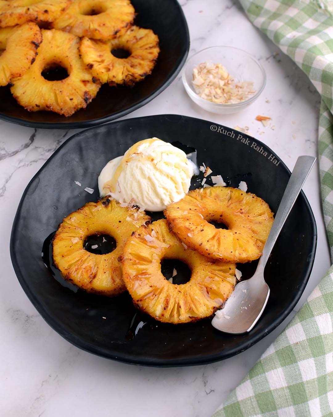 Air fried pineapples with ice cream & honey on black plate.