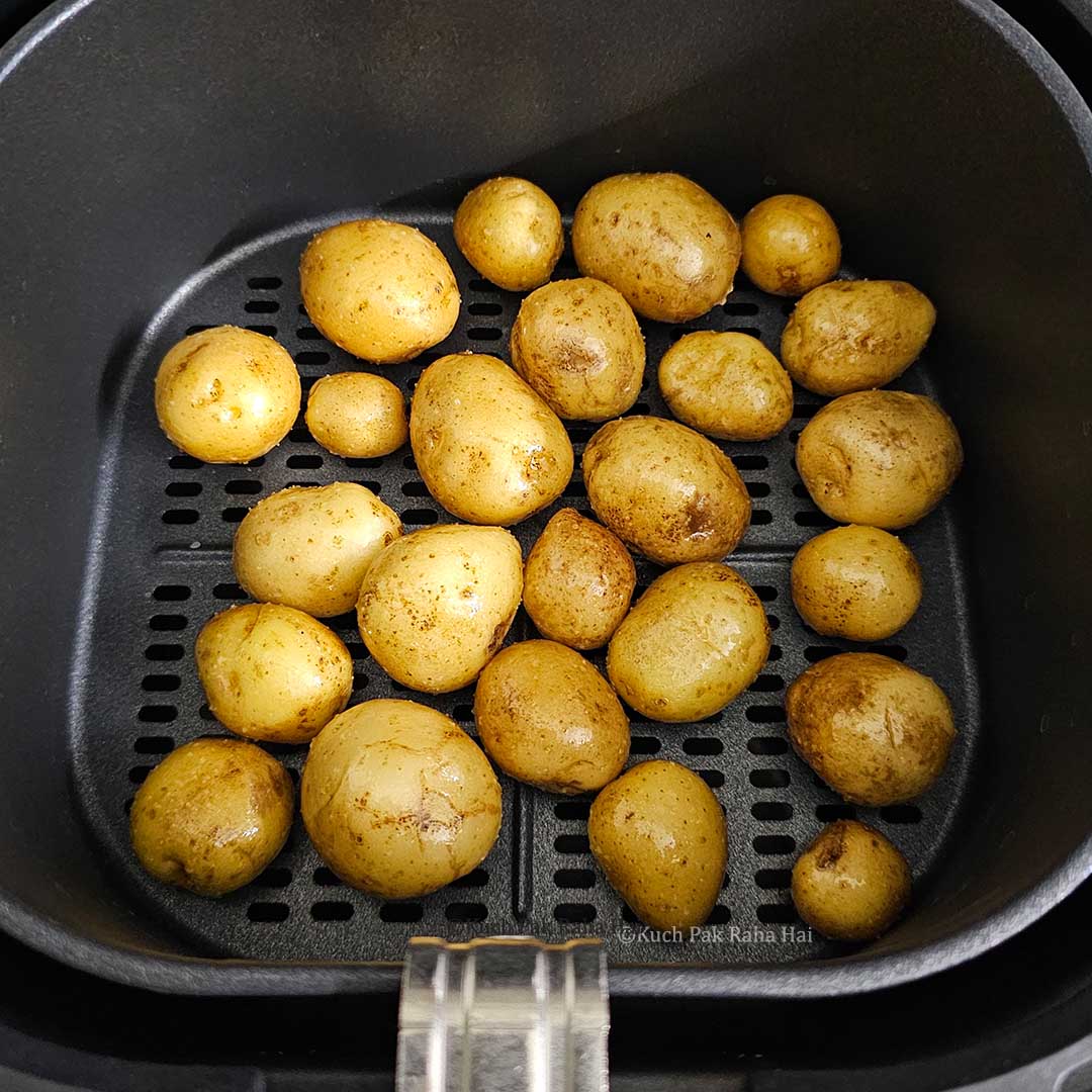 Transferring potatoes in air fryer basket.