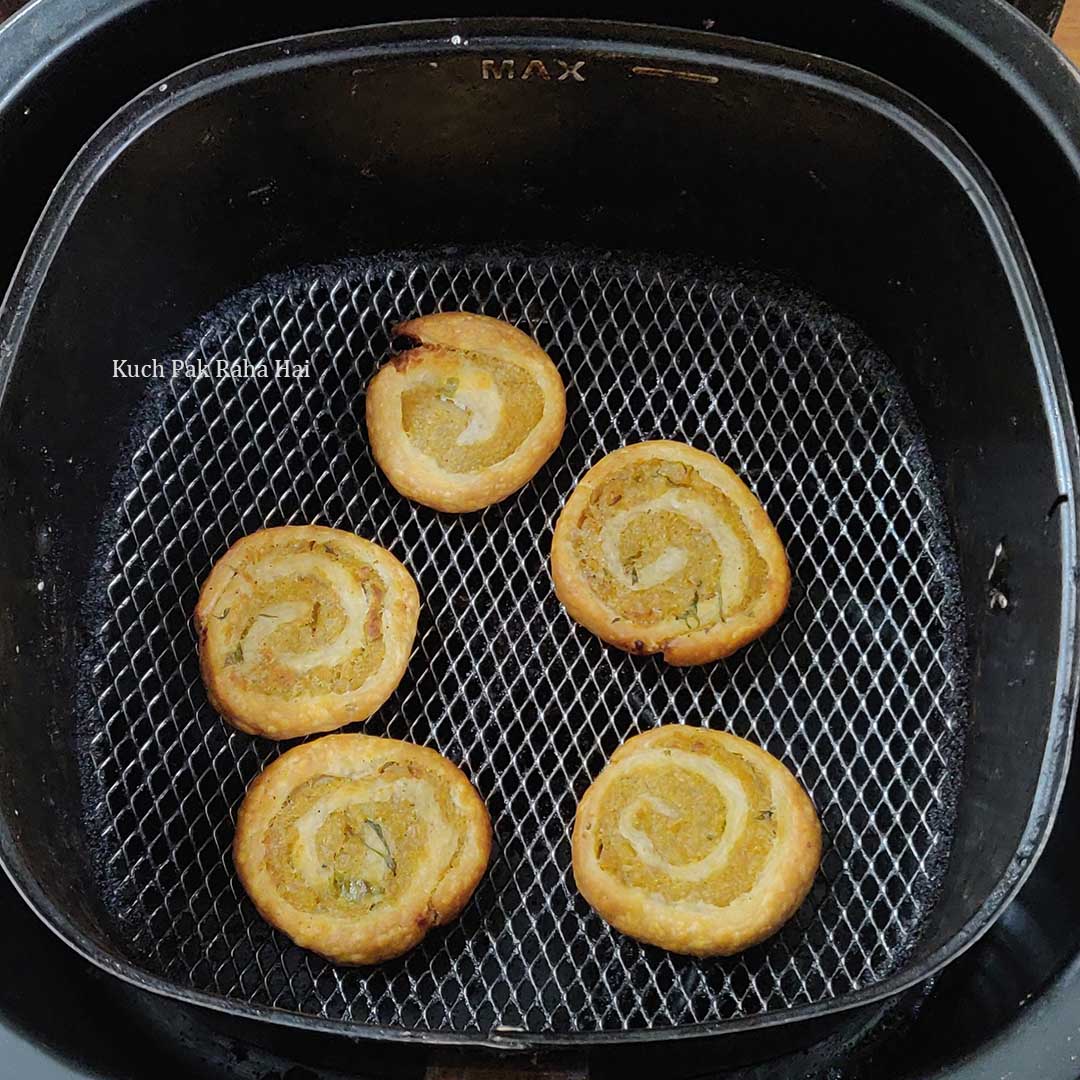 Air fried pinwheel samosa in air fryer basket.