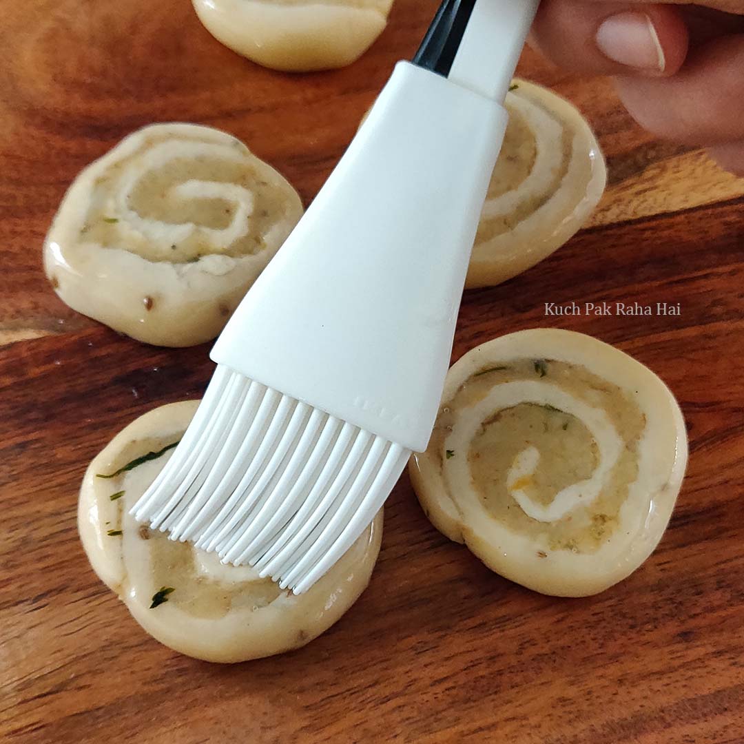 Brushing oil on pinwheel samosa before air frying.