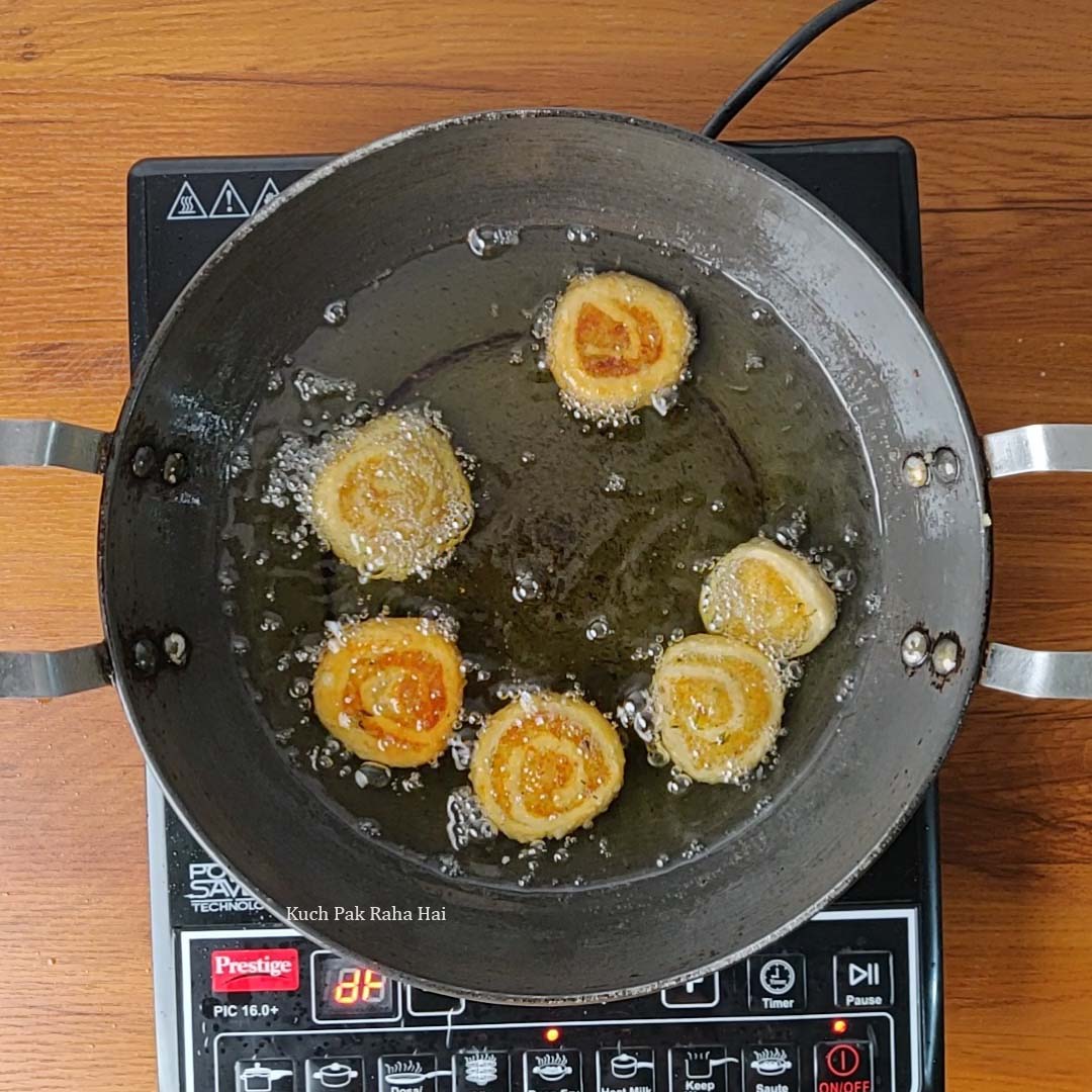 Deep frying pinwheel samosa on stovetop.