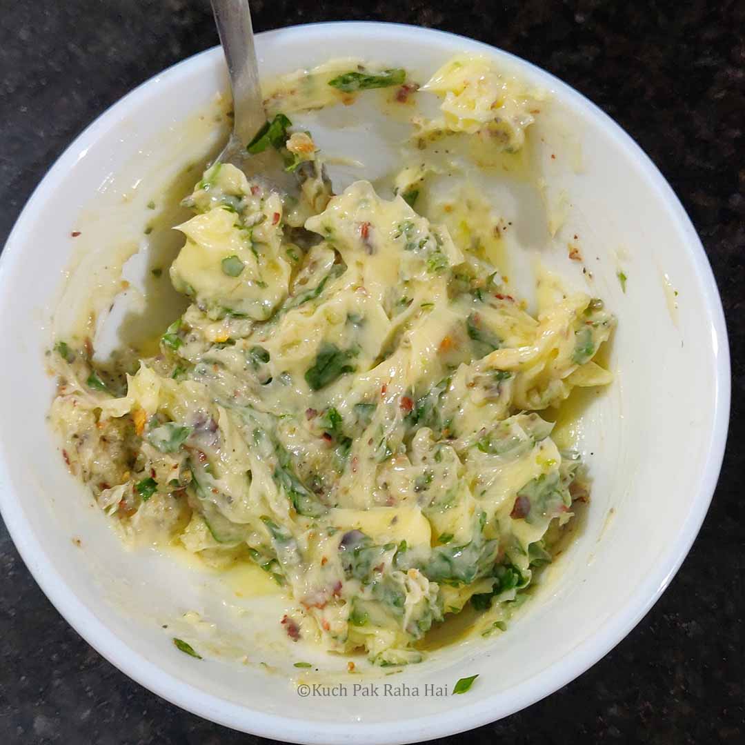 Mixing softened butter with herbs & spices.