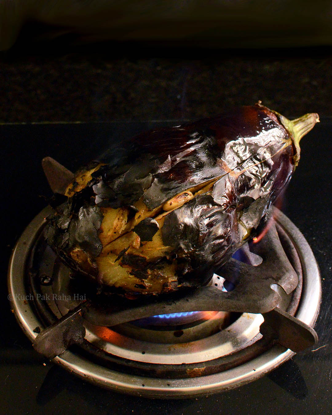 Eggplant (baingan) being roasted on fire.