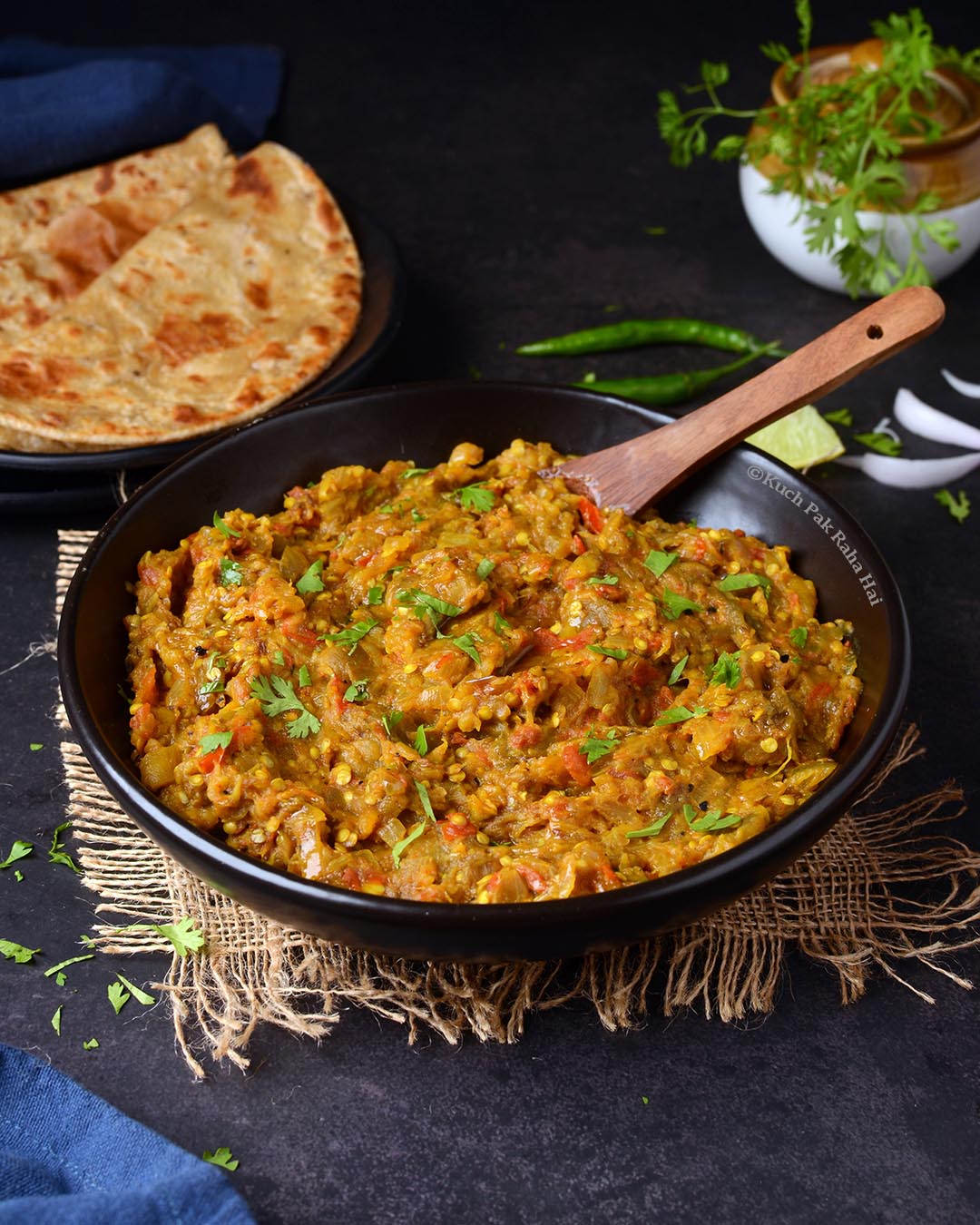 Baingan Bharta in black bowl served with paratha.