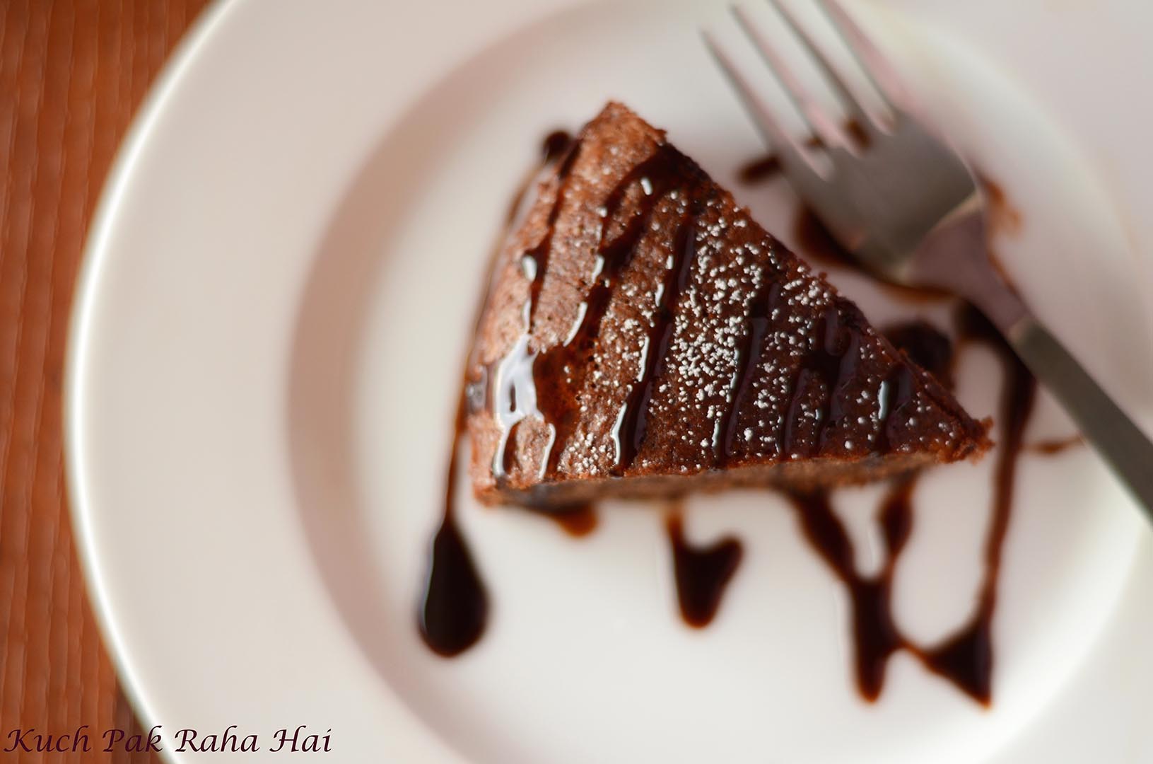 Eggless Chocolate Cake slice drizzled with chocolate syrup.