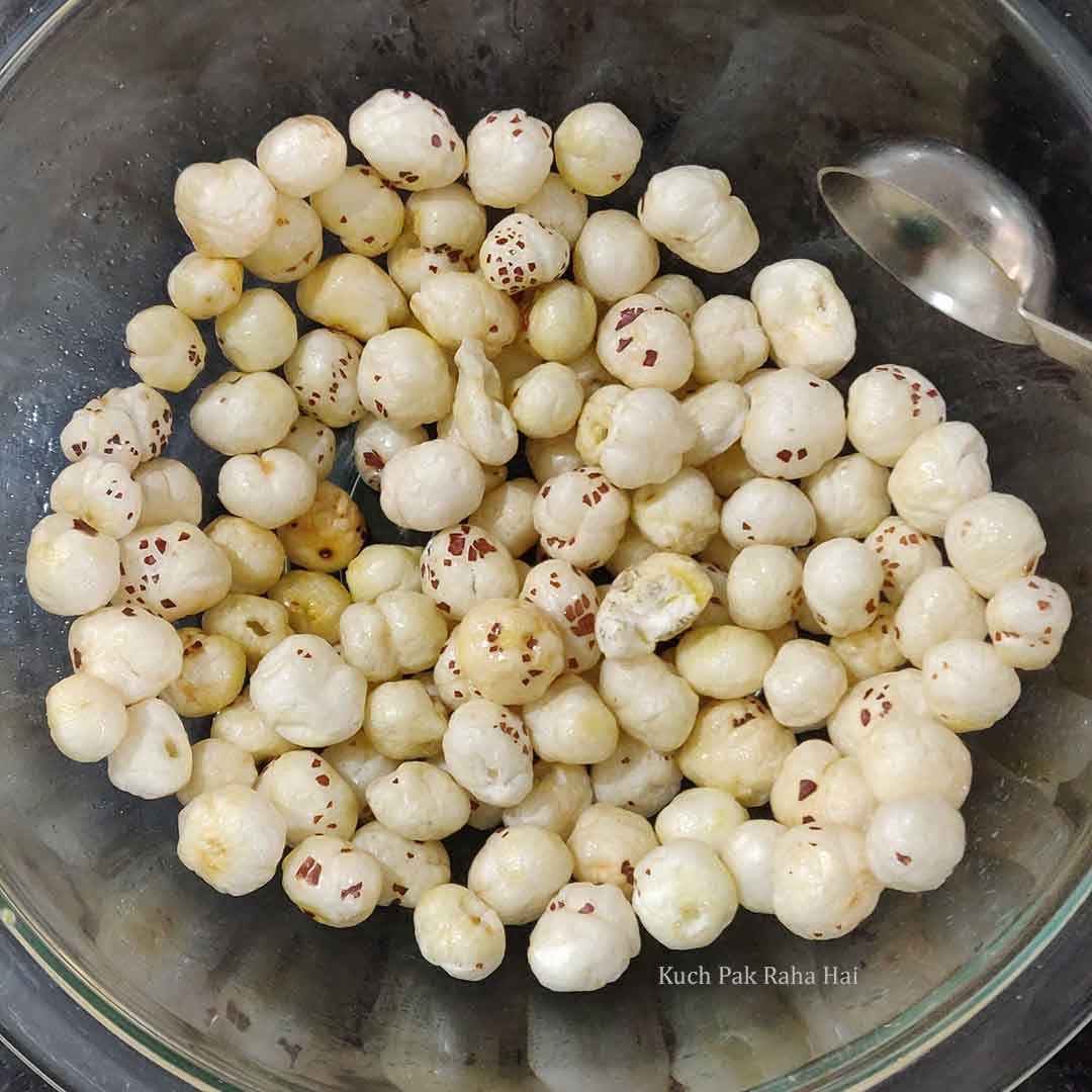 Adding melted ghee to makhana (lotus seeds).