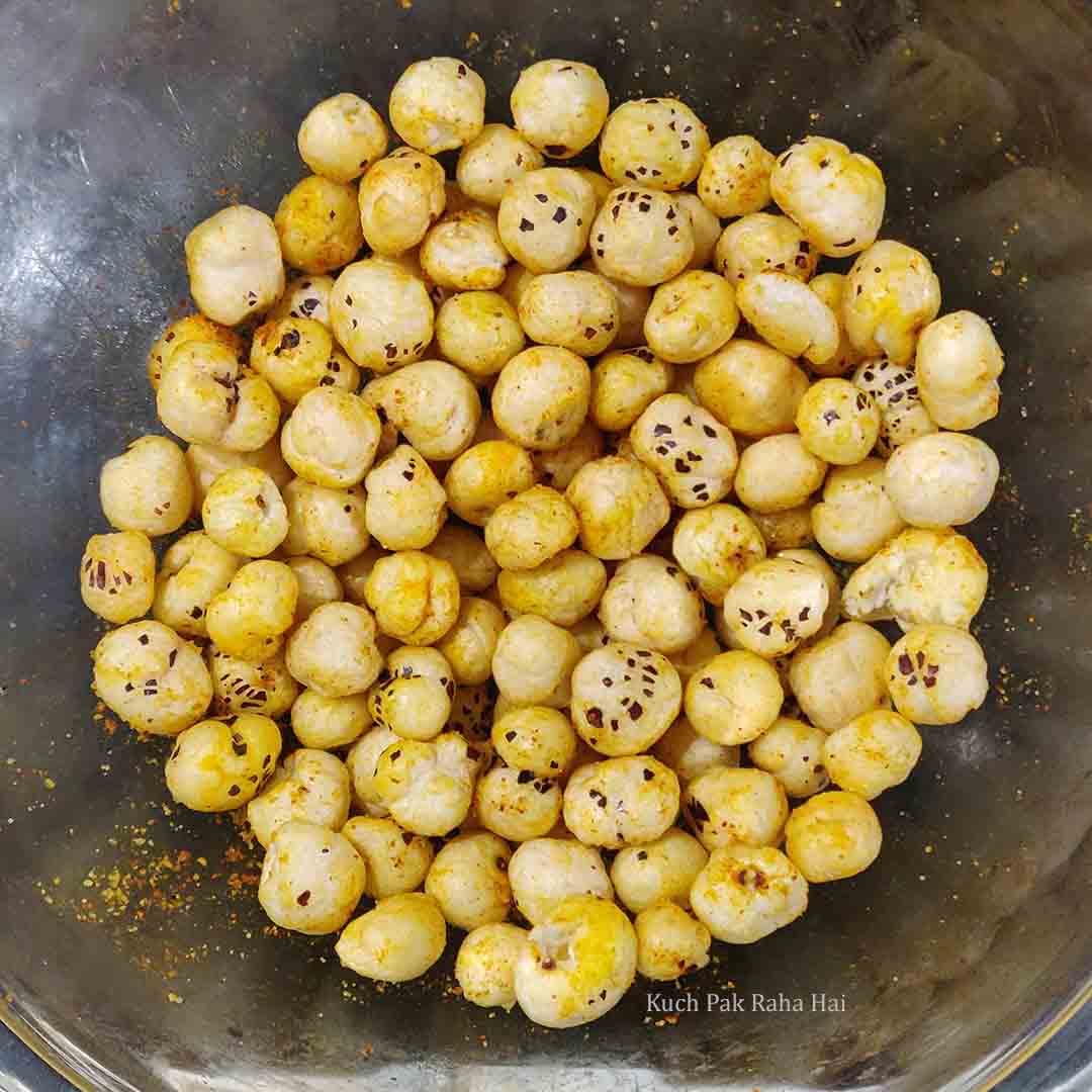 Adding spices to roasted makhana.