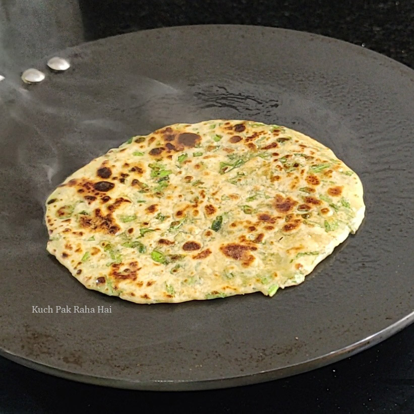 Cooking palak paratha on tawa or pan.