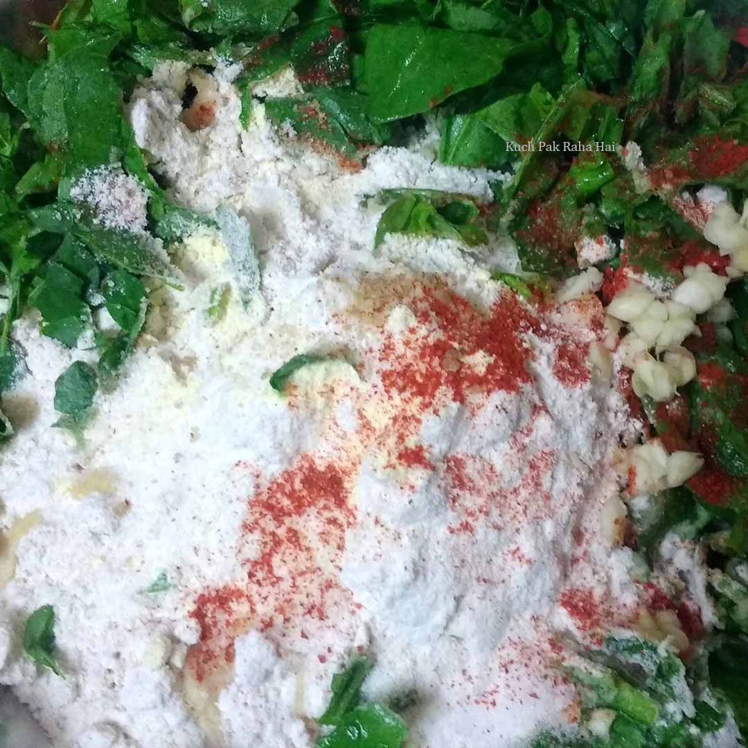 Mixing chopped spinach methi with flour and spices.