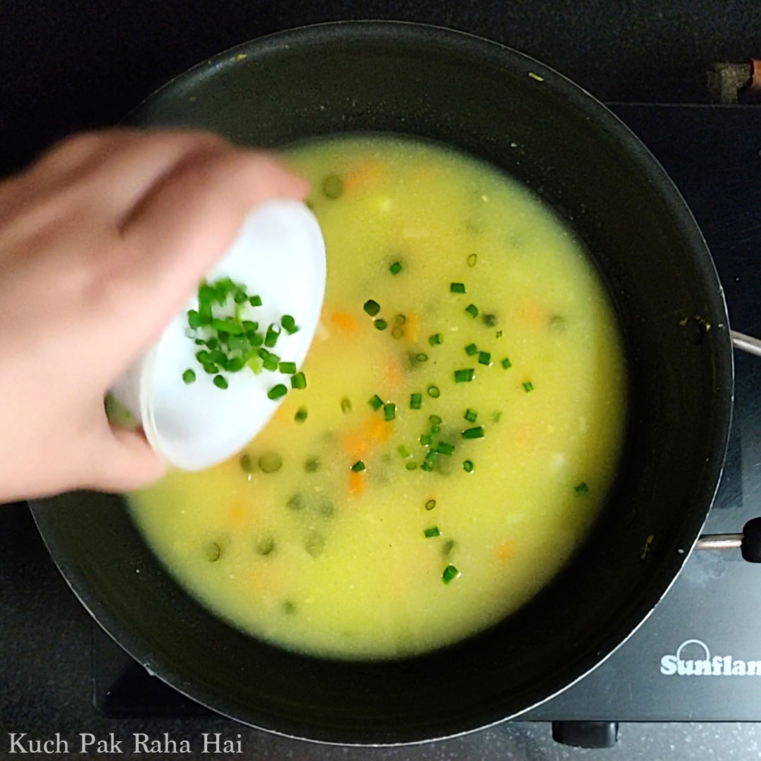Garnishing corn soup with spring onion greens.