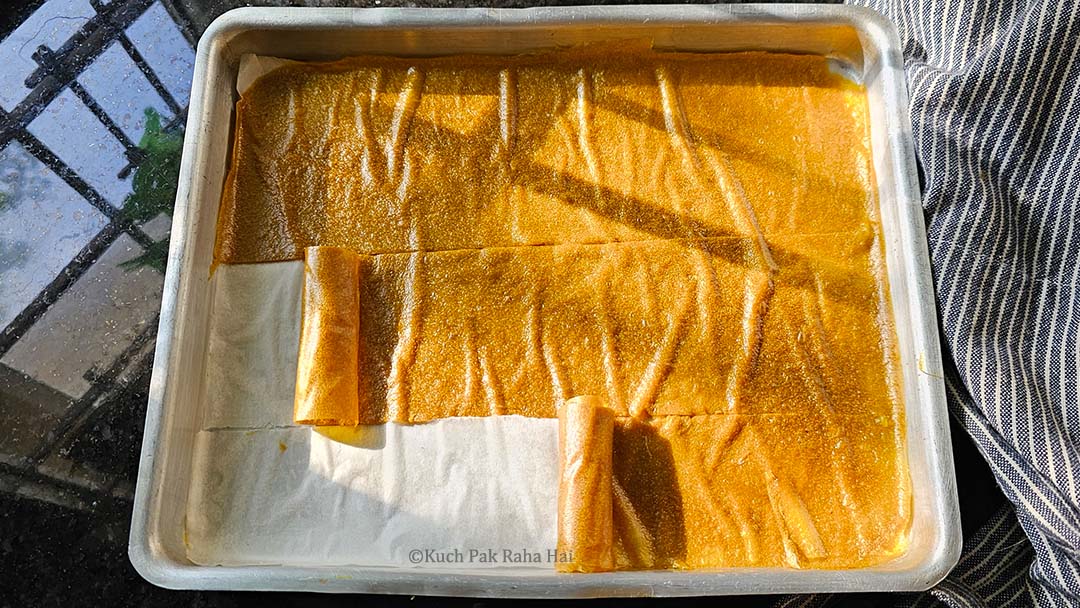 Cutting mango fruit sheet into strips and rolling it.