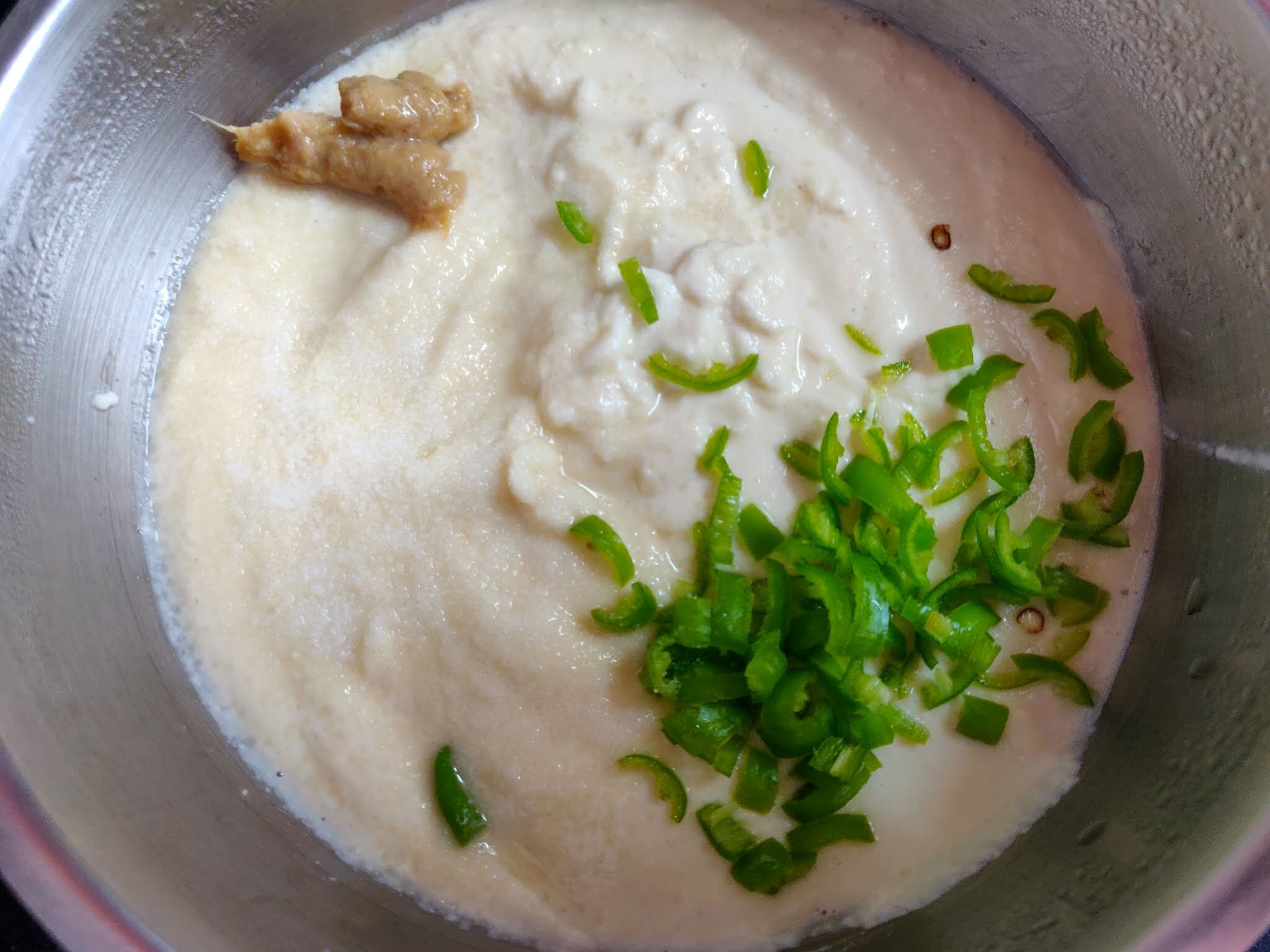 Adding seasoning to idli batter.