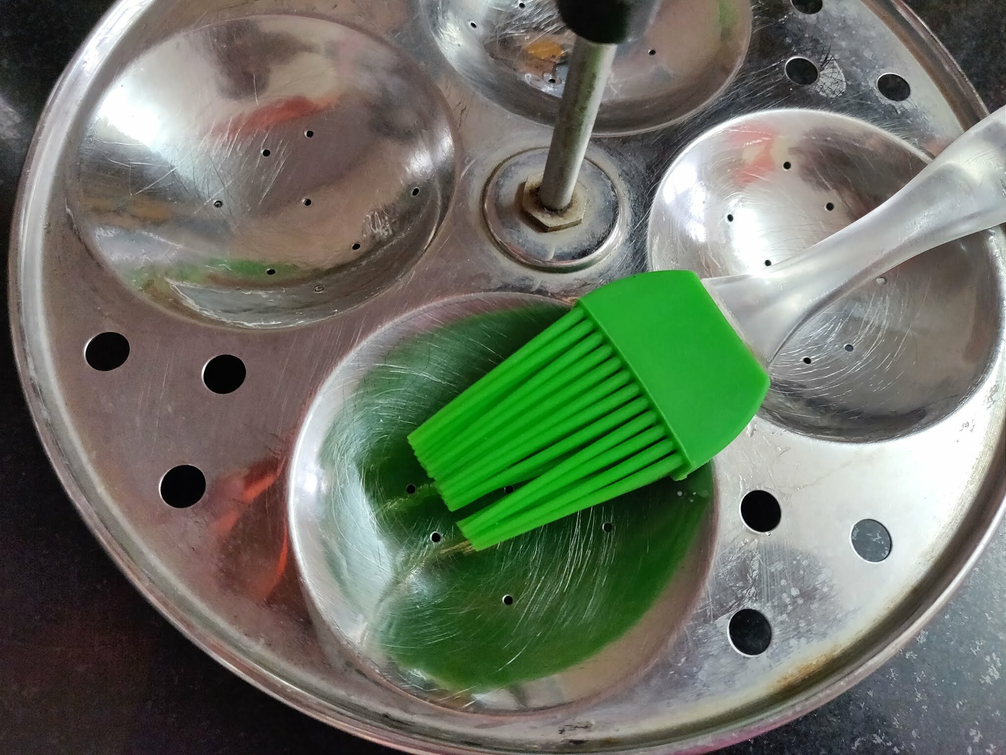 Brushing oil on idli plates.