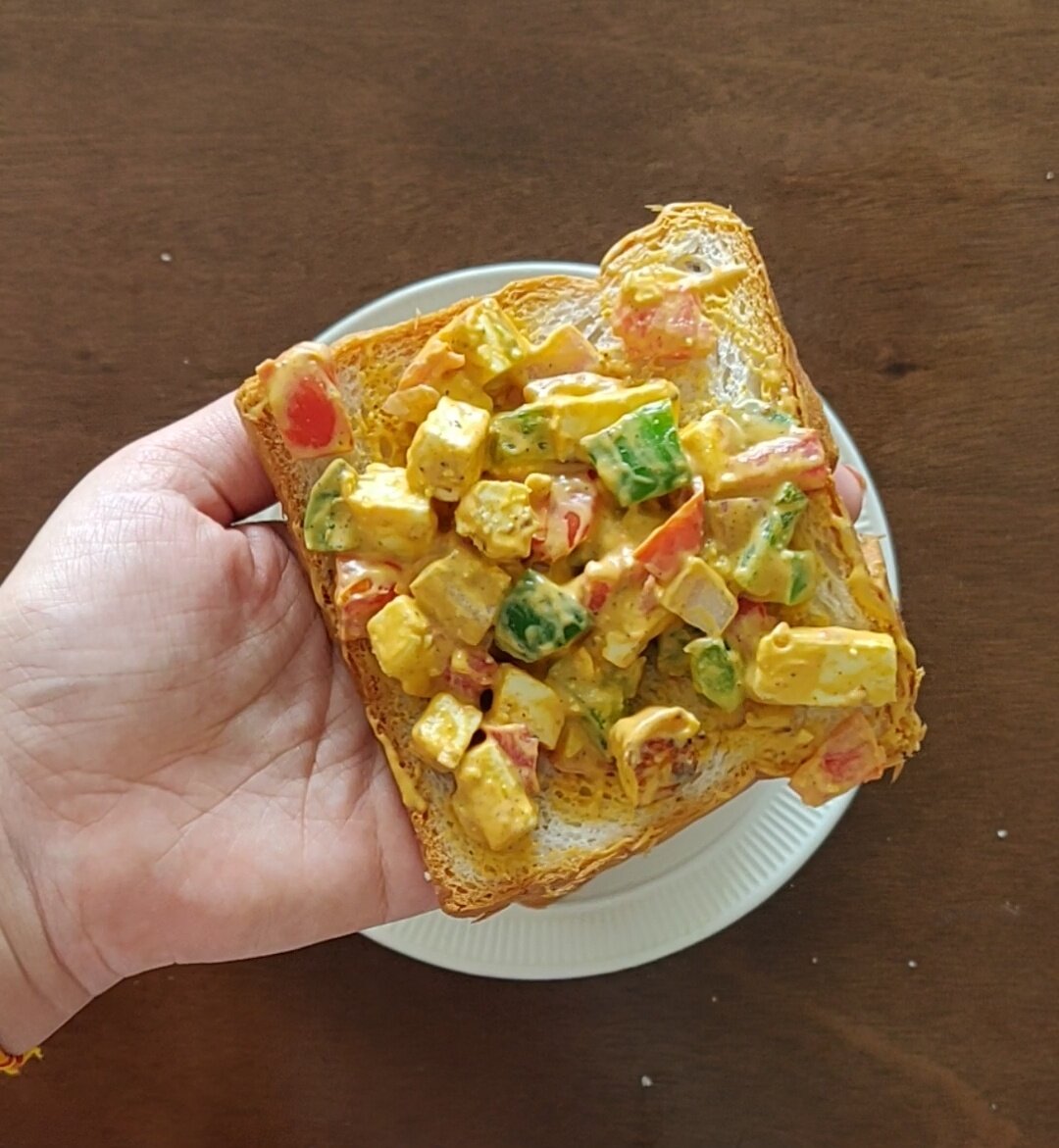 Spreading paneer filling on bread slice.