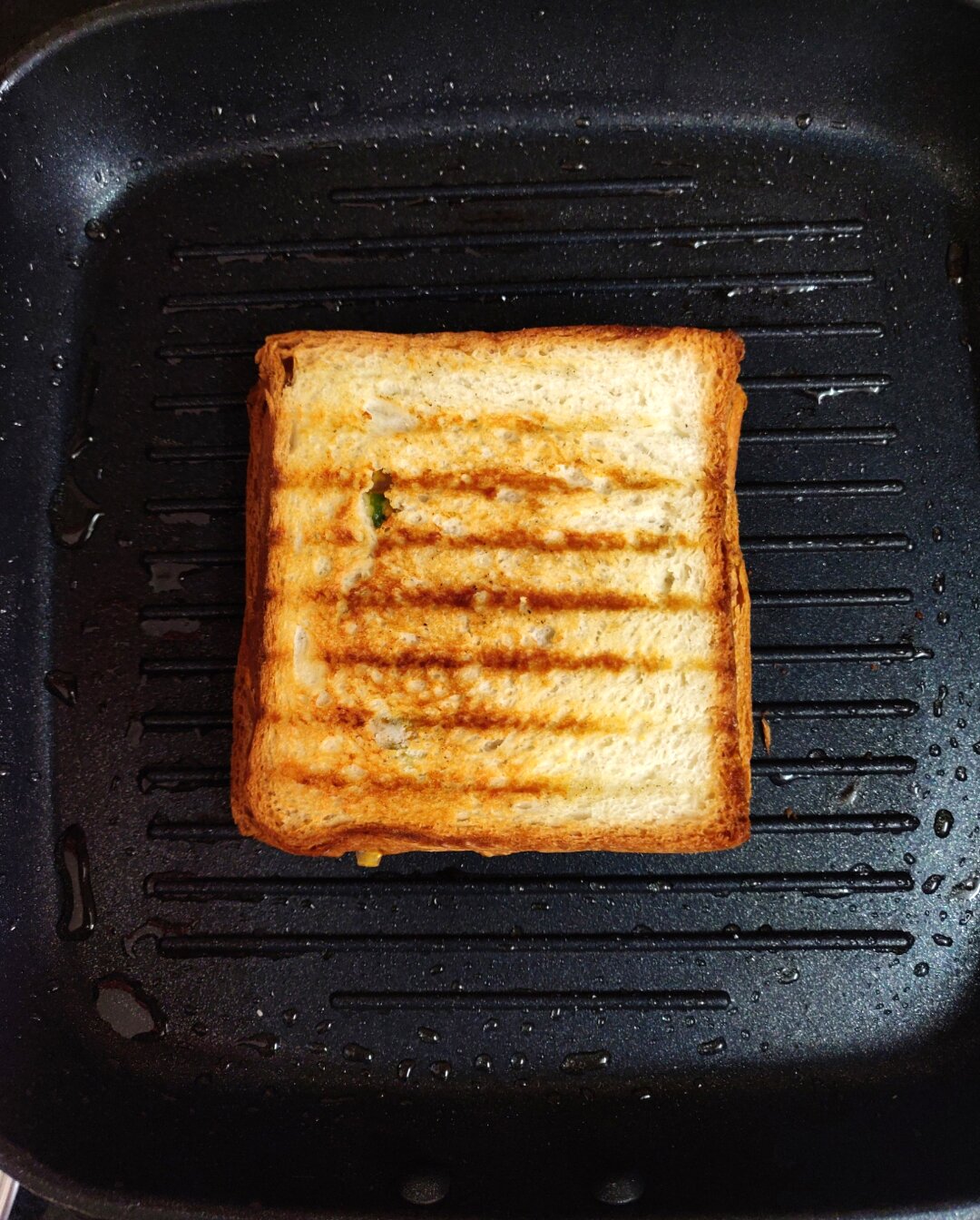 Grilling paneer tikka sandwich on a pan.