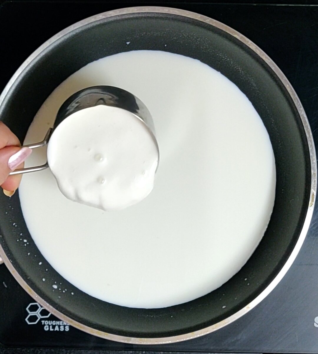 Adding heavy cream to heated milk.