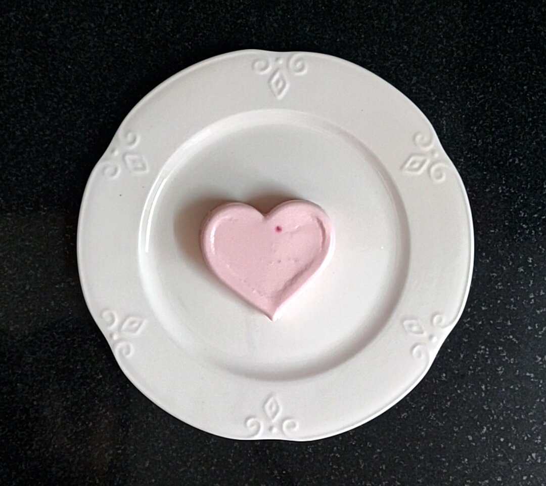 Heart shaped panna cotta on white plate.