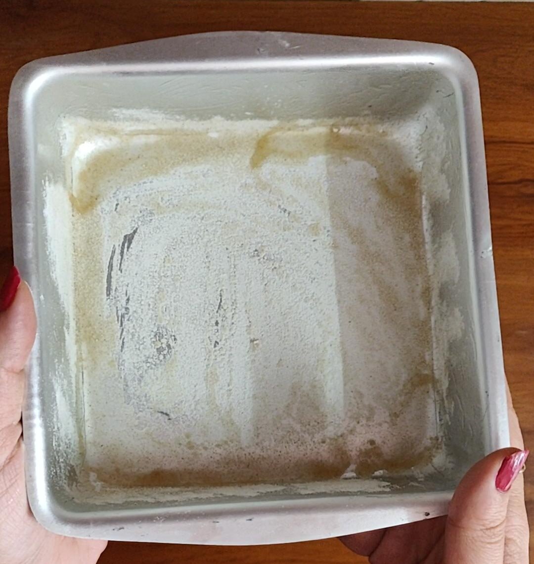 Dusting and greasing cake pan before baking.