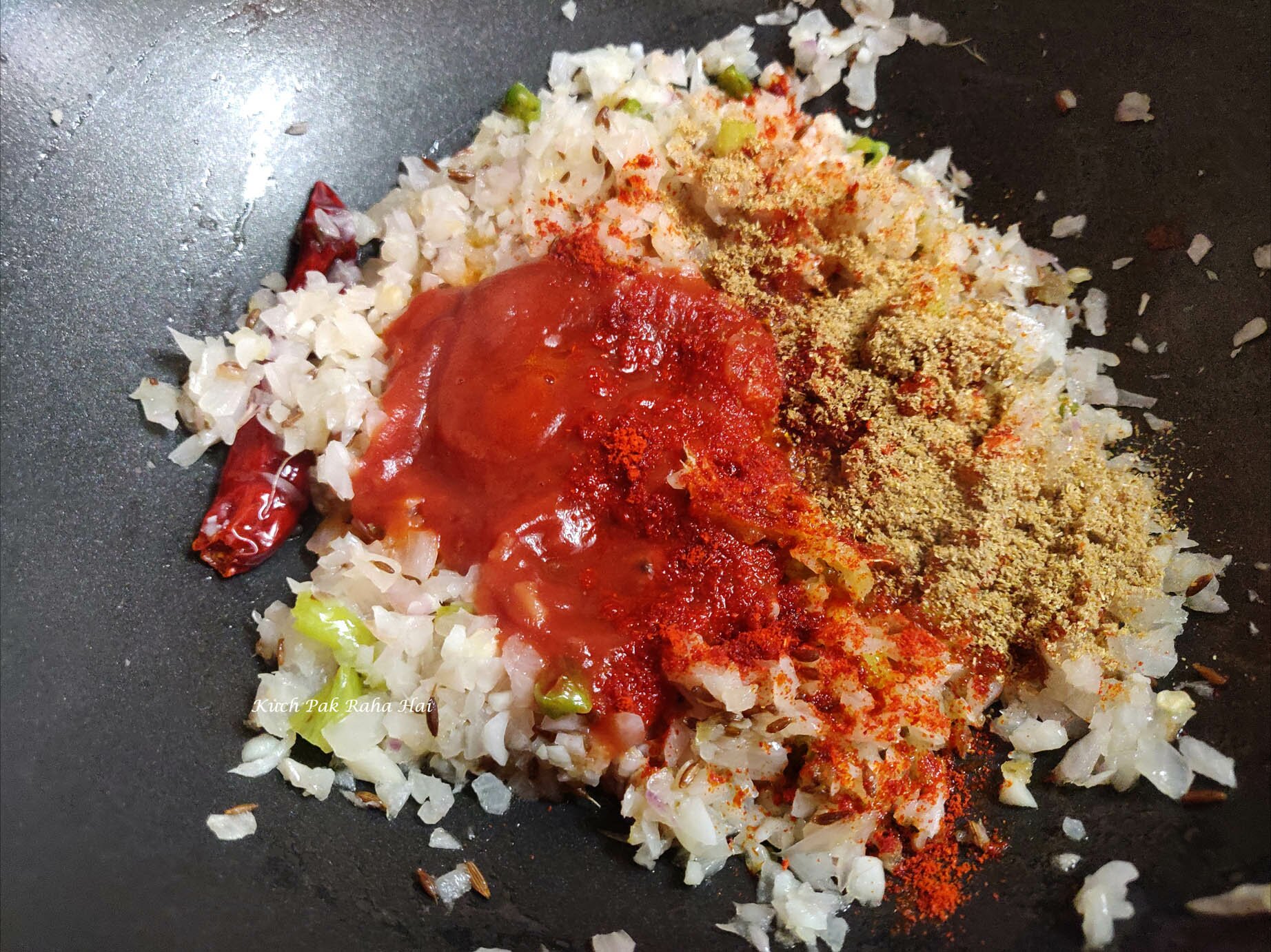 Adding tomato puree and spices to make masala for dal.