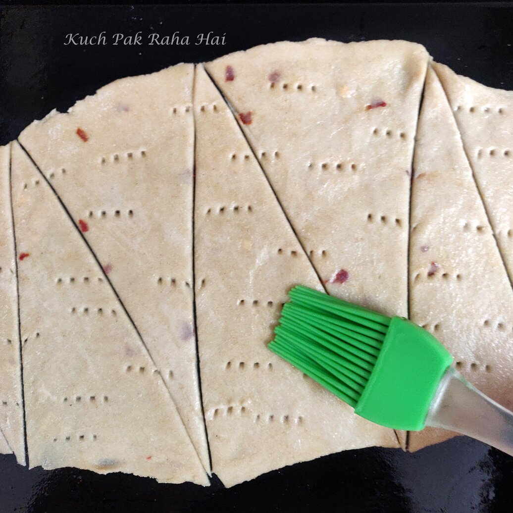 Brushing olive oil on raw lavash chips.