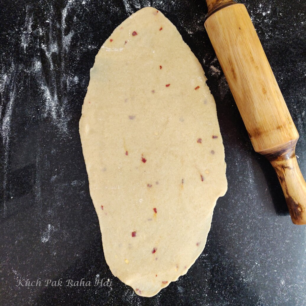 Rolling the dough with the help of rolling pin.