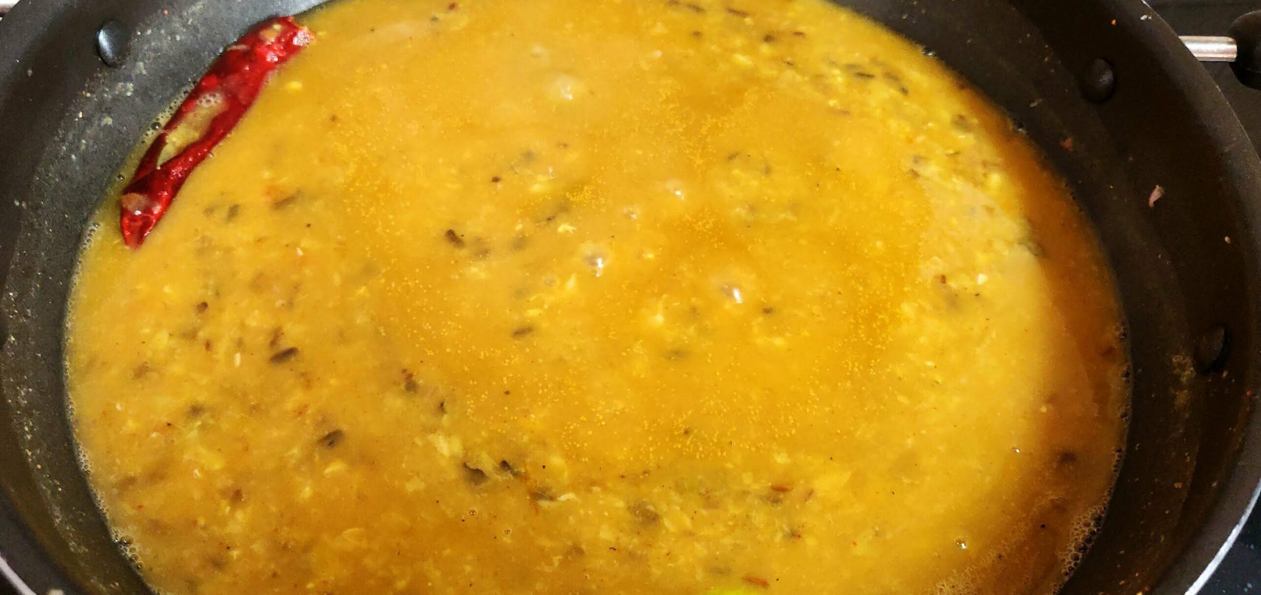 Adding boiled lentils to masala and cooking it.