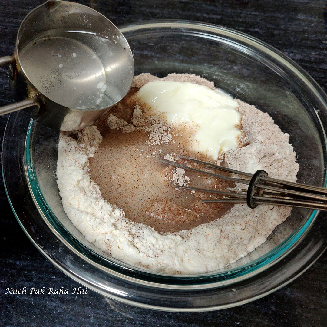 Adding water to make ragi dosa batter.