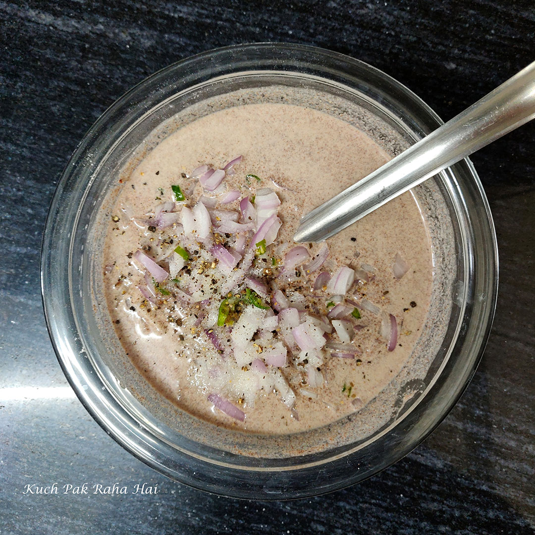 Adding chopped onion, spices to ragi dosa batter.