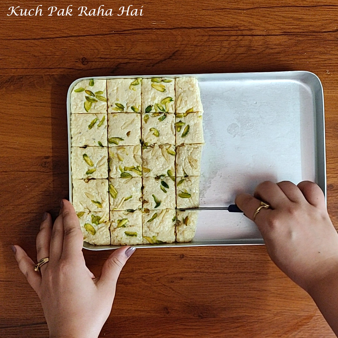 Cutting kalakand squares using knife.