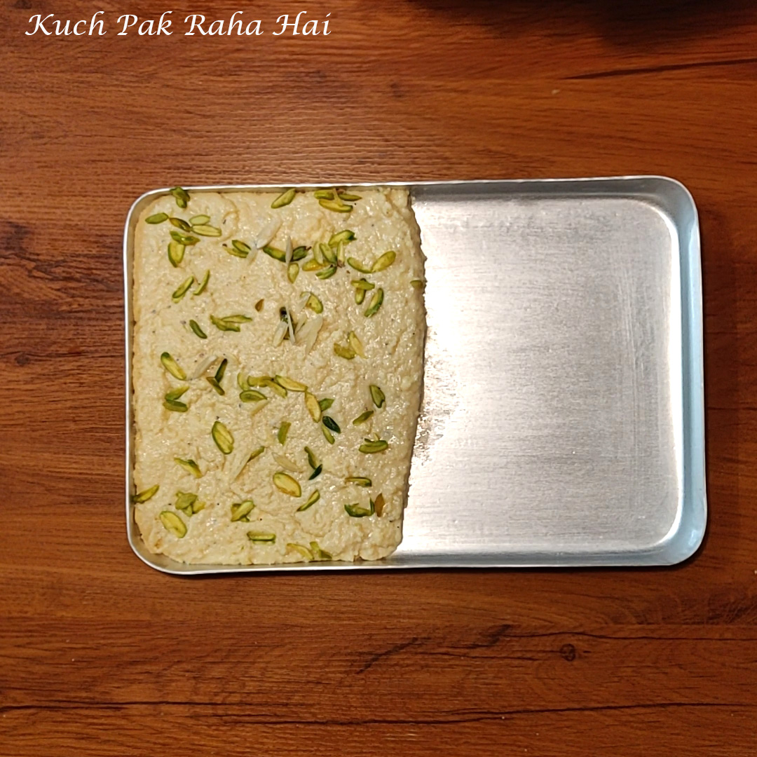 Setting milk kalakand in a greased tray.