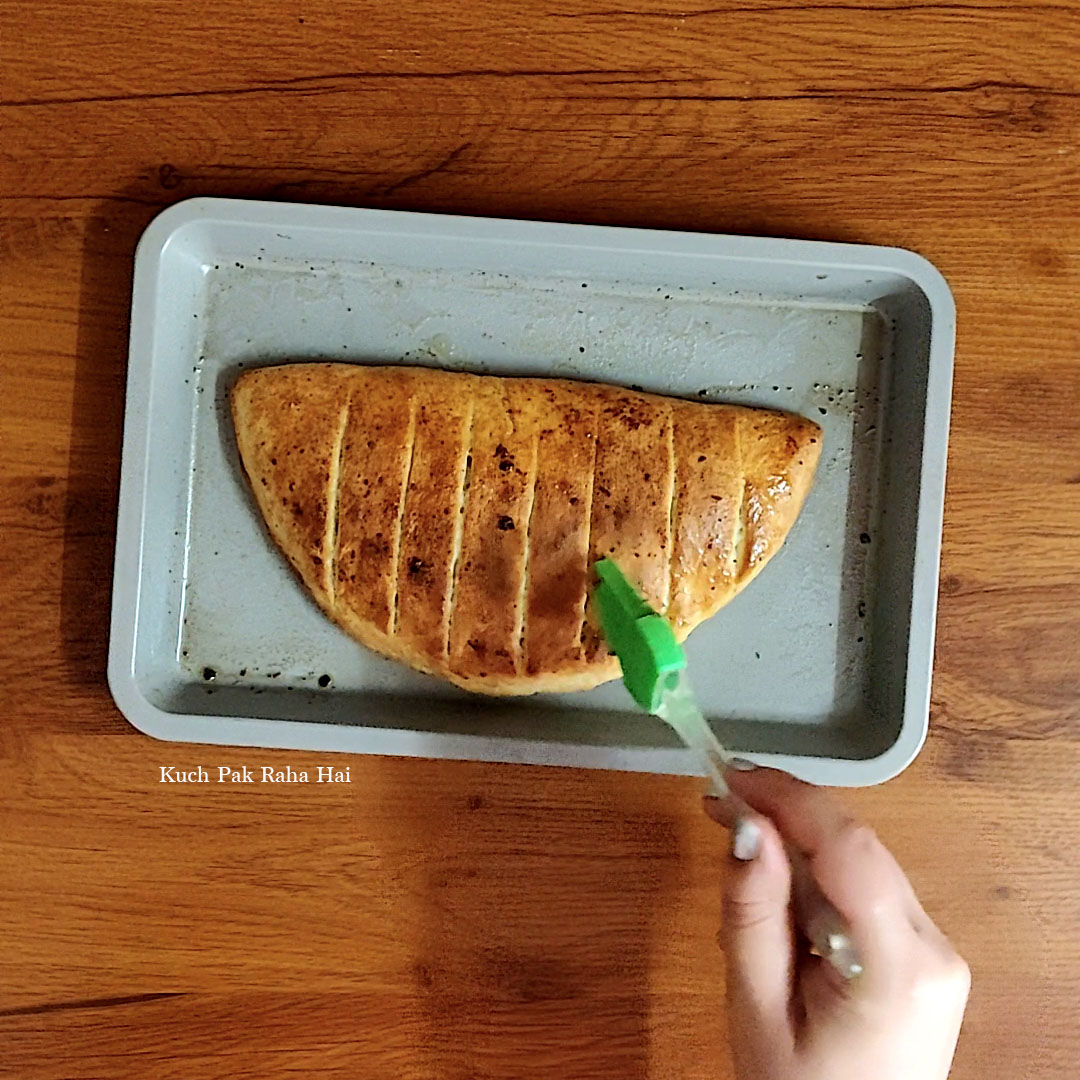 Brushing garlic butter on baked bread.