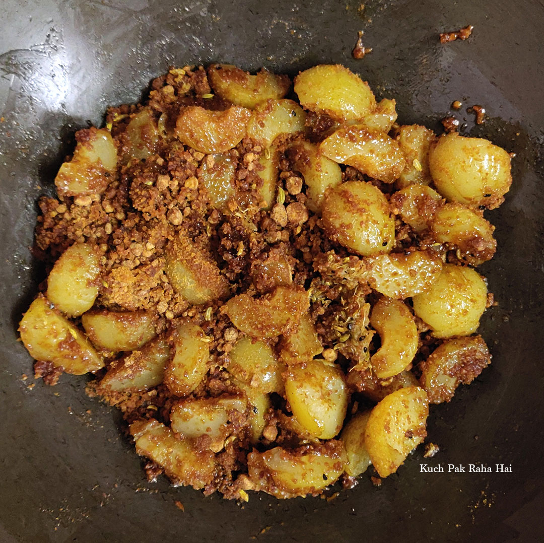 Adding cooked amla and jaggery to roasted spices.