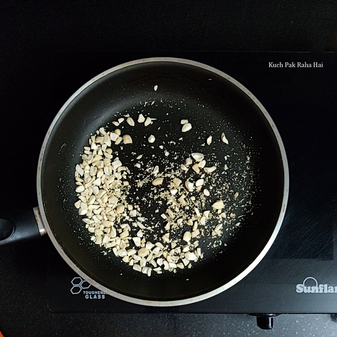 Roasting chopped cashews in a pan.