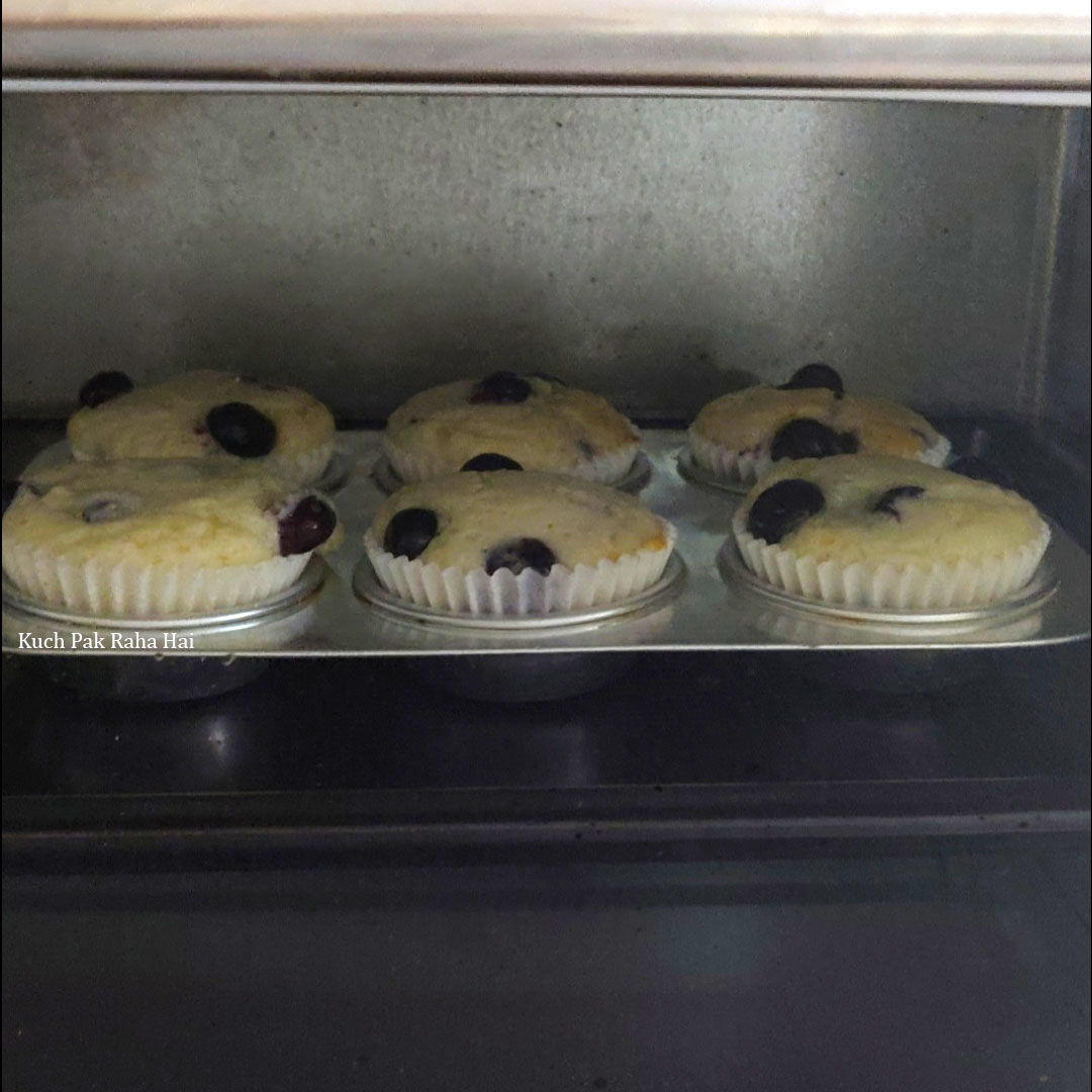 Blueberry muffin baking in oven.