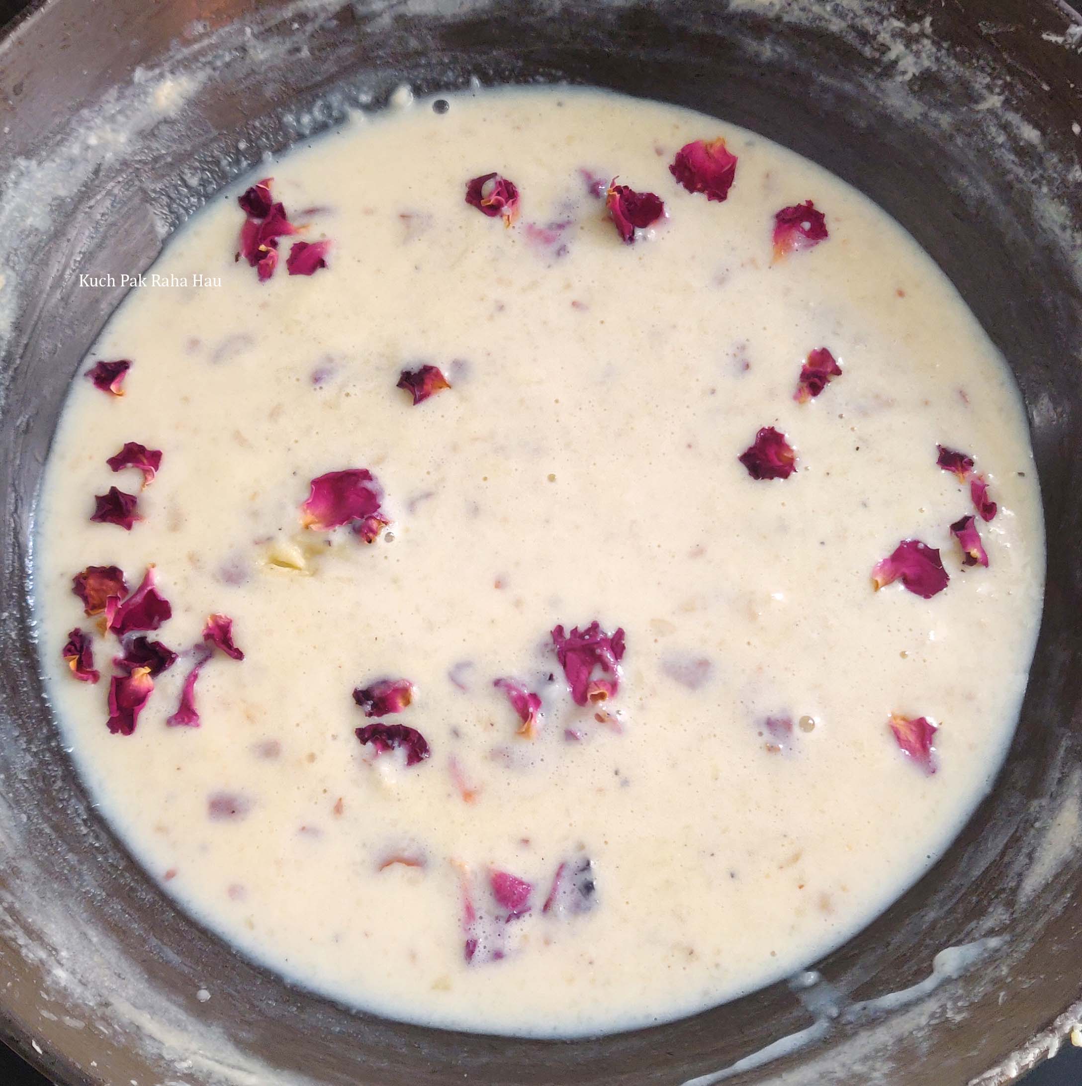 Adding rose water, petals to kulfi mixture.