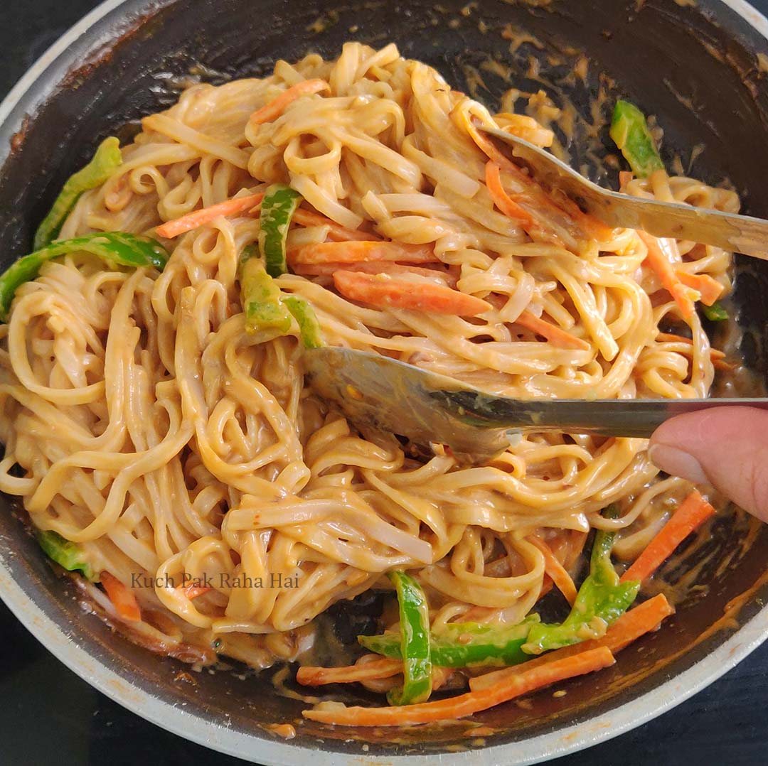 Mixing rice noodles with peanut sauce.