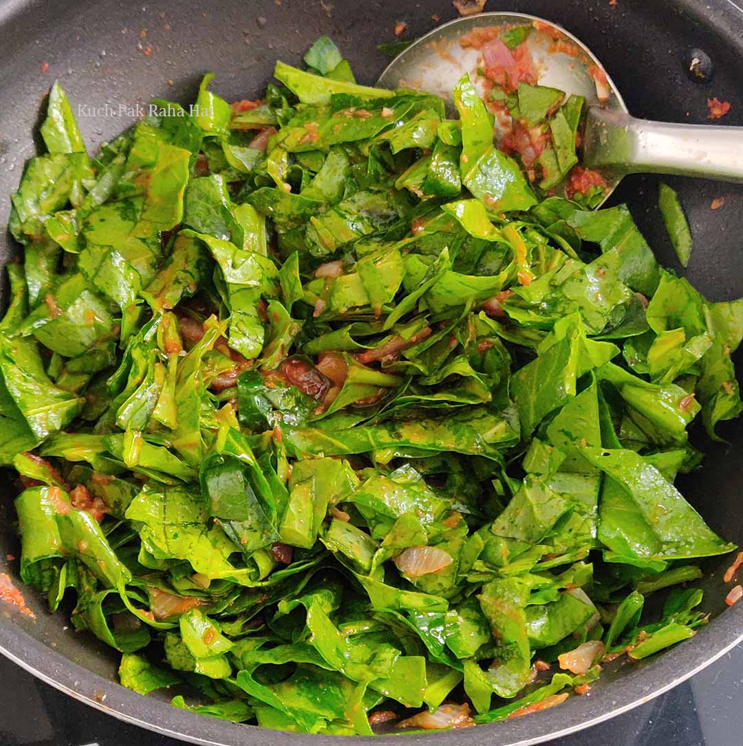 Adding spinach to masala mixture.