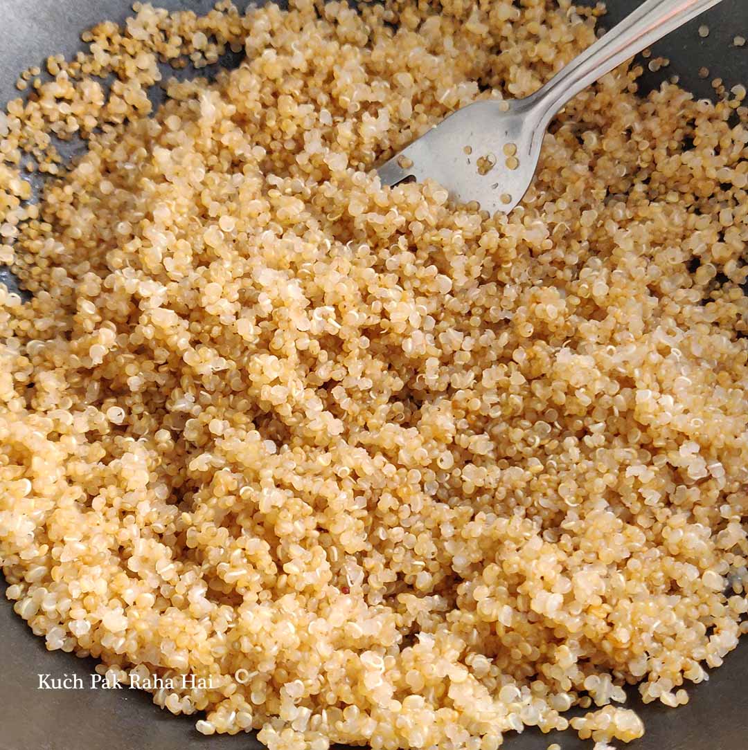 Fluffing boiled quinoa with fork.