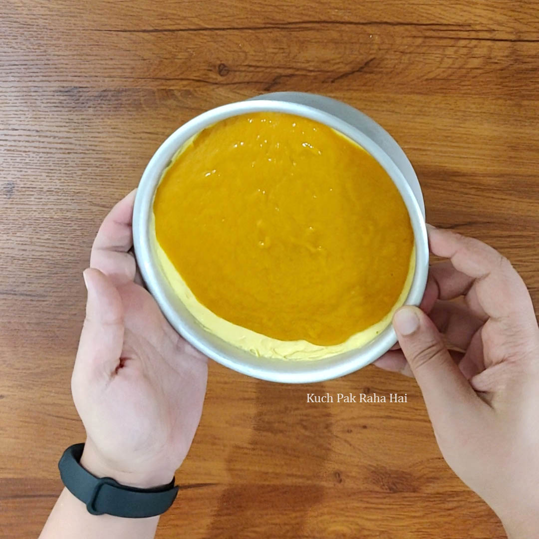 Pouring mango jelly mixture on mango cheesecake.