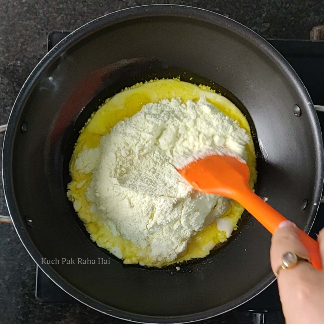 Adding milk powder to the pan and mixing with spatula.