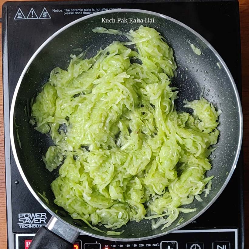 Sautéing grated dudhi in ghee.