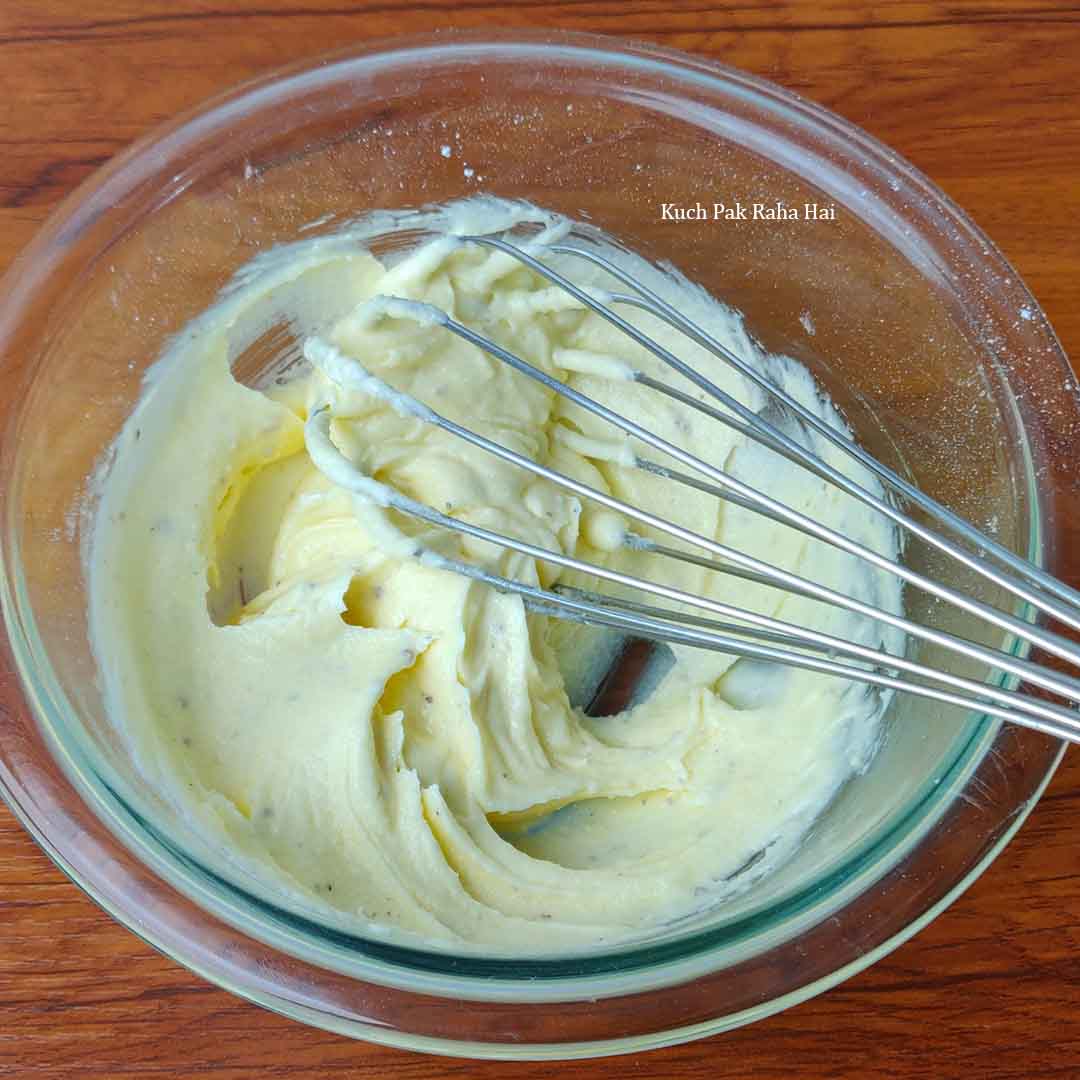 Whisking ghee and sugar with cardamom.